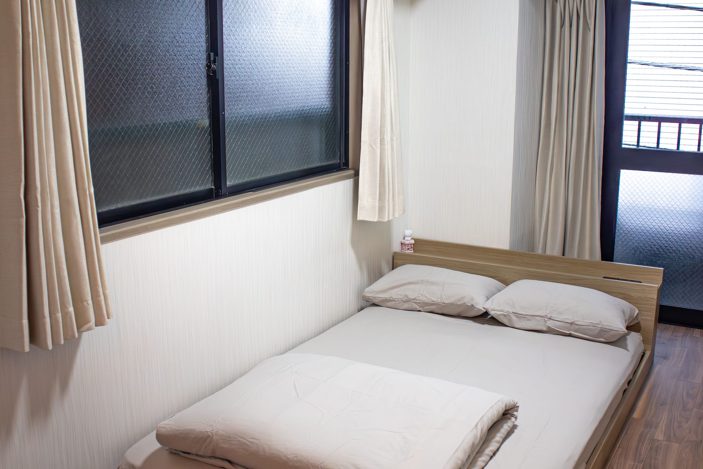 Double bed with white linens and a small wooden table.