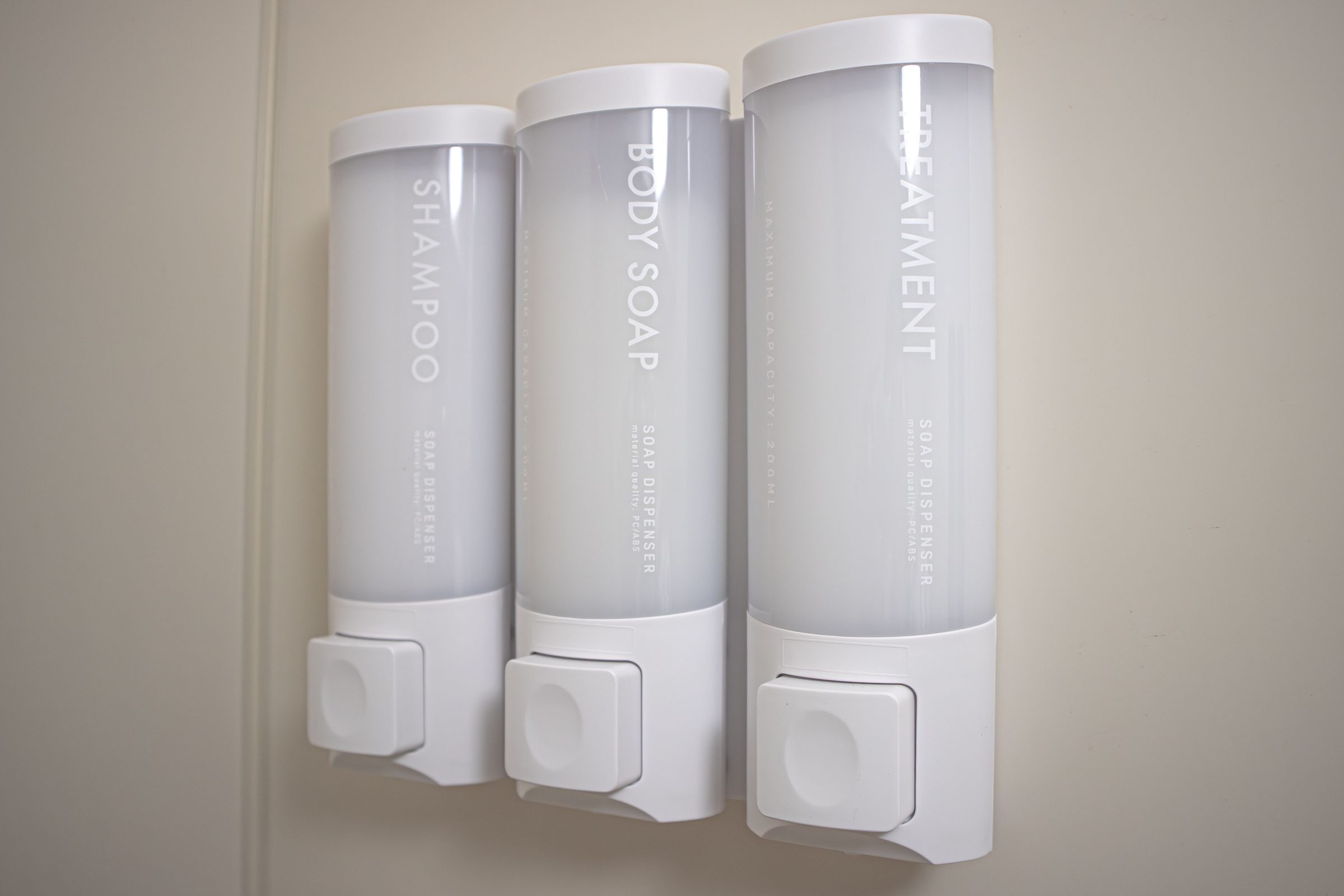 Wall-mounted dispensers for shampoo, body soap, and treatment.
