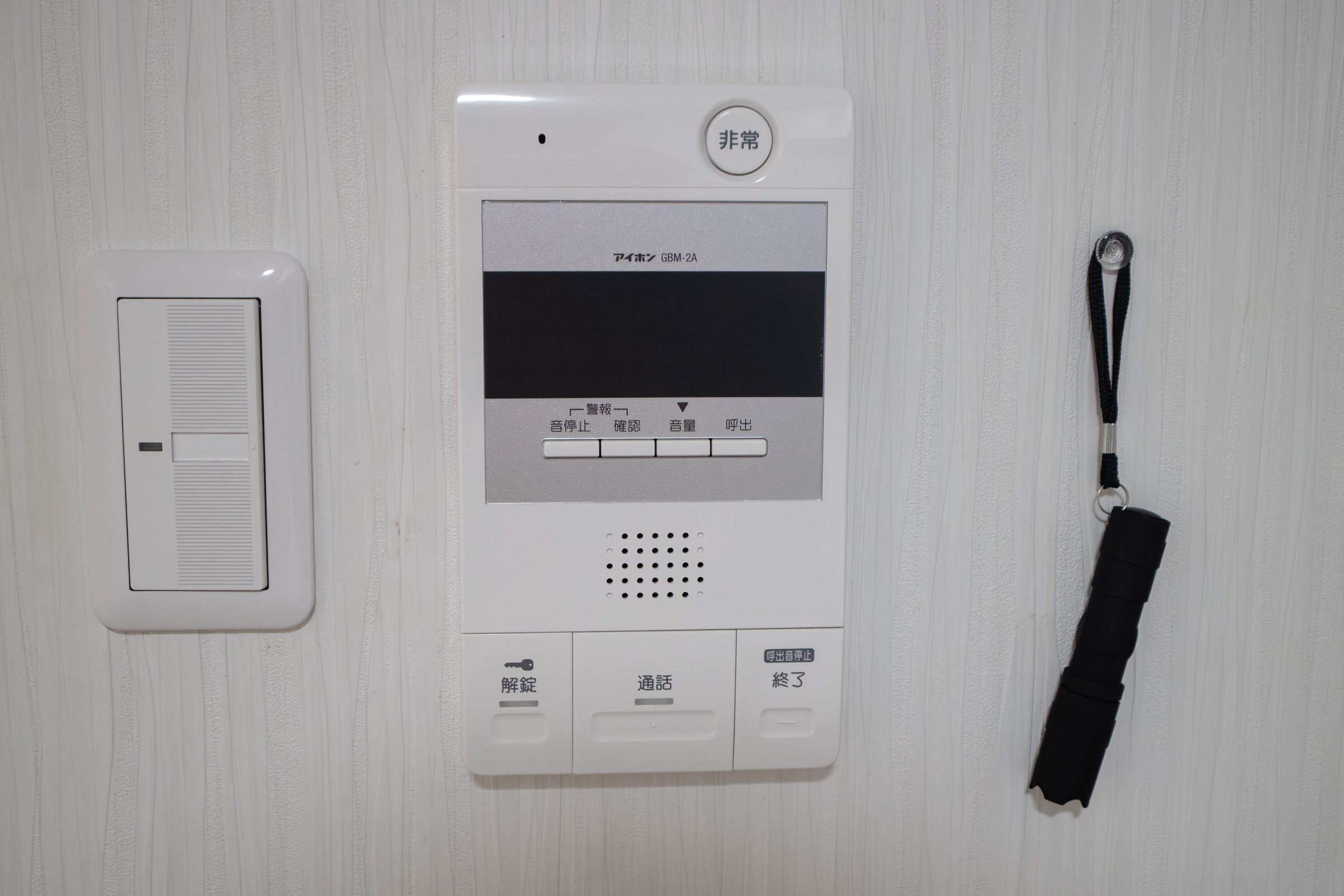 Intercom system and flashlight on a white wall.