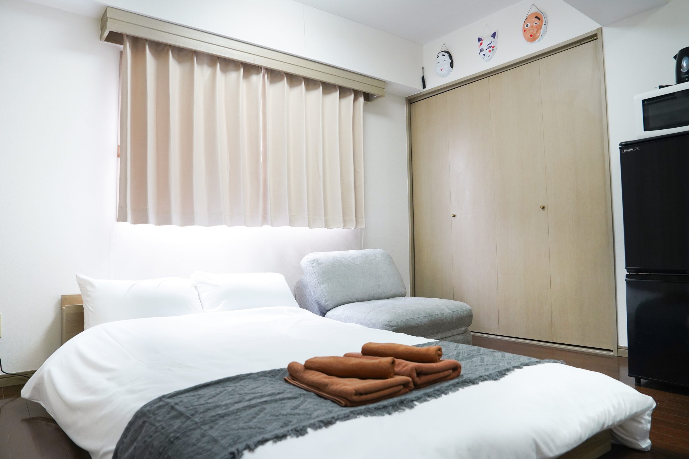 Bedroom with a double bed, grey lounge chair and closet.