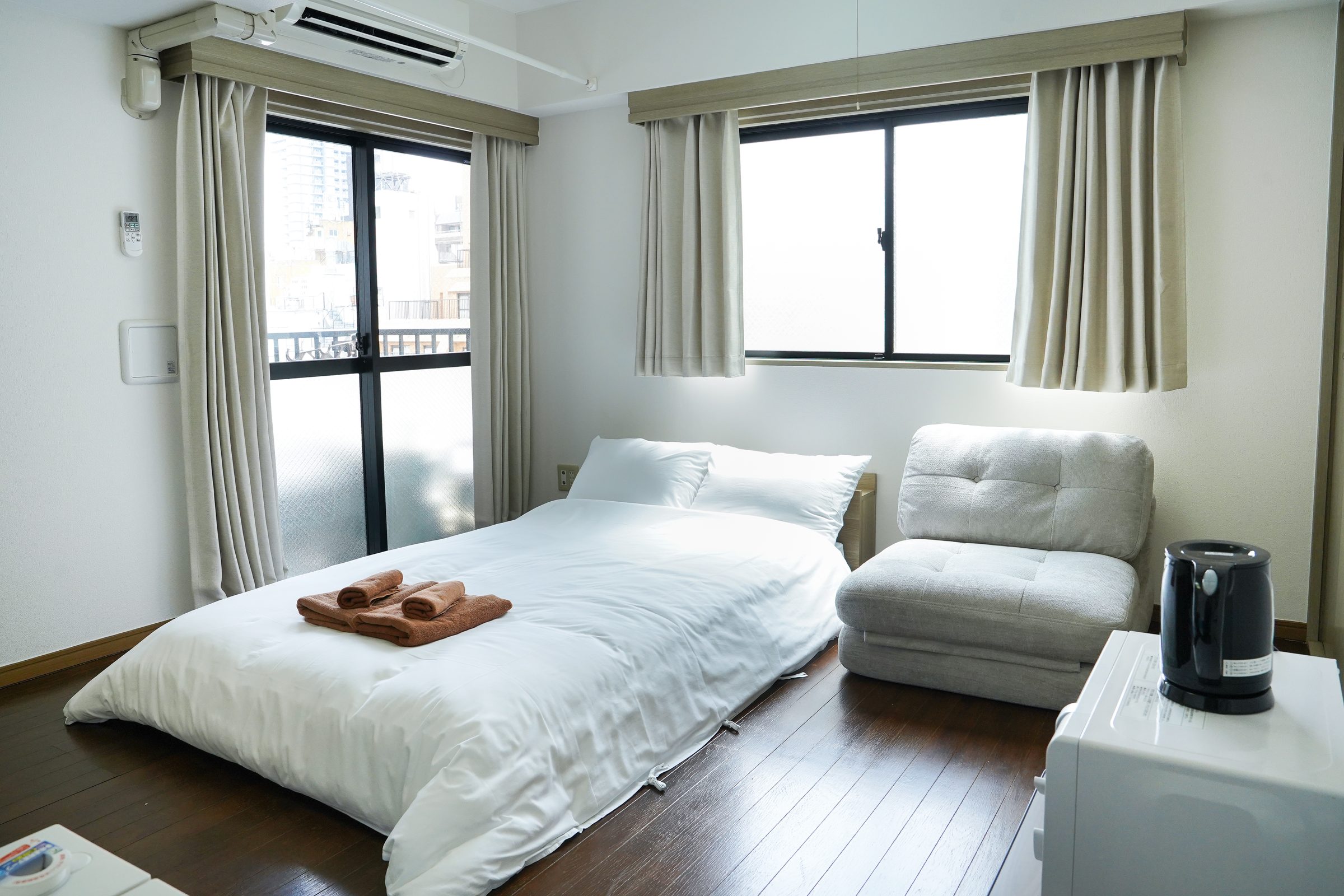 Bright bedroom with a double bed and a grey sofa.