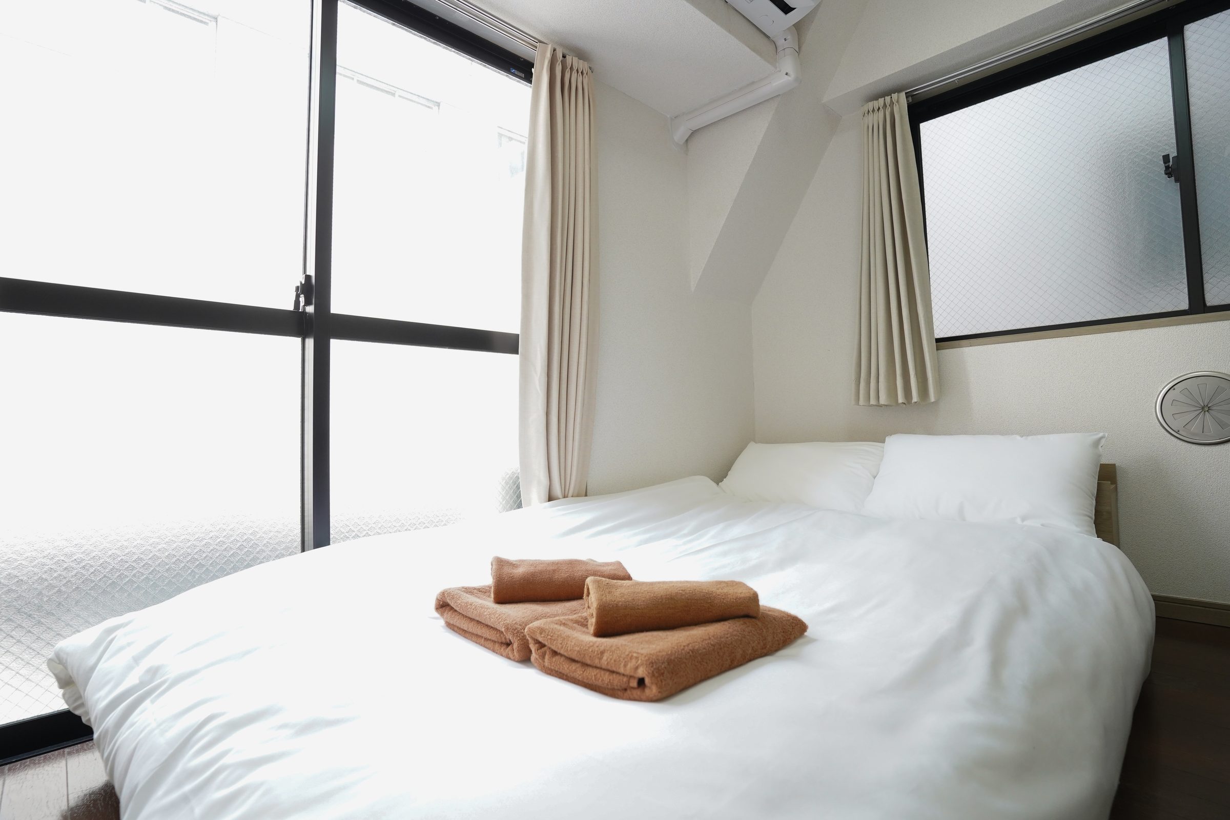 Bedroom with a large bed, white linens and brown towels.