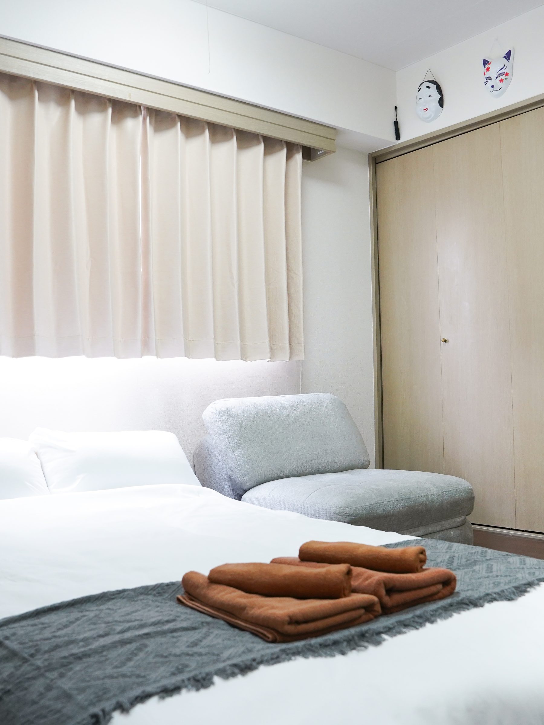 Bedroom with a double bed, grey lounge chair and closet.